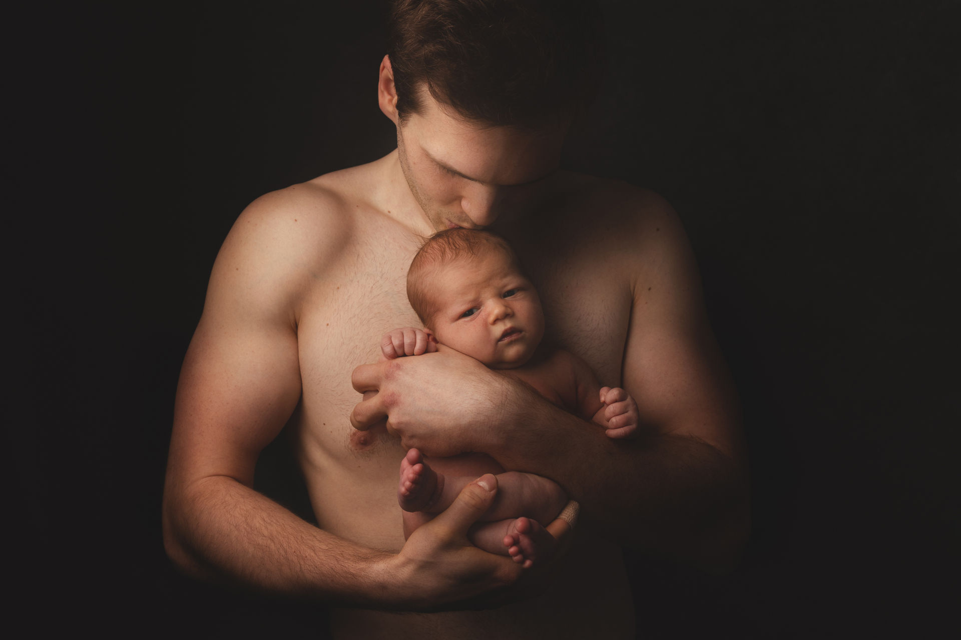 Vater hält sein Neugeborenes behutsam im Arm