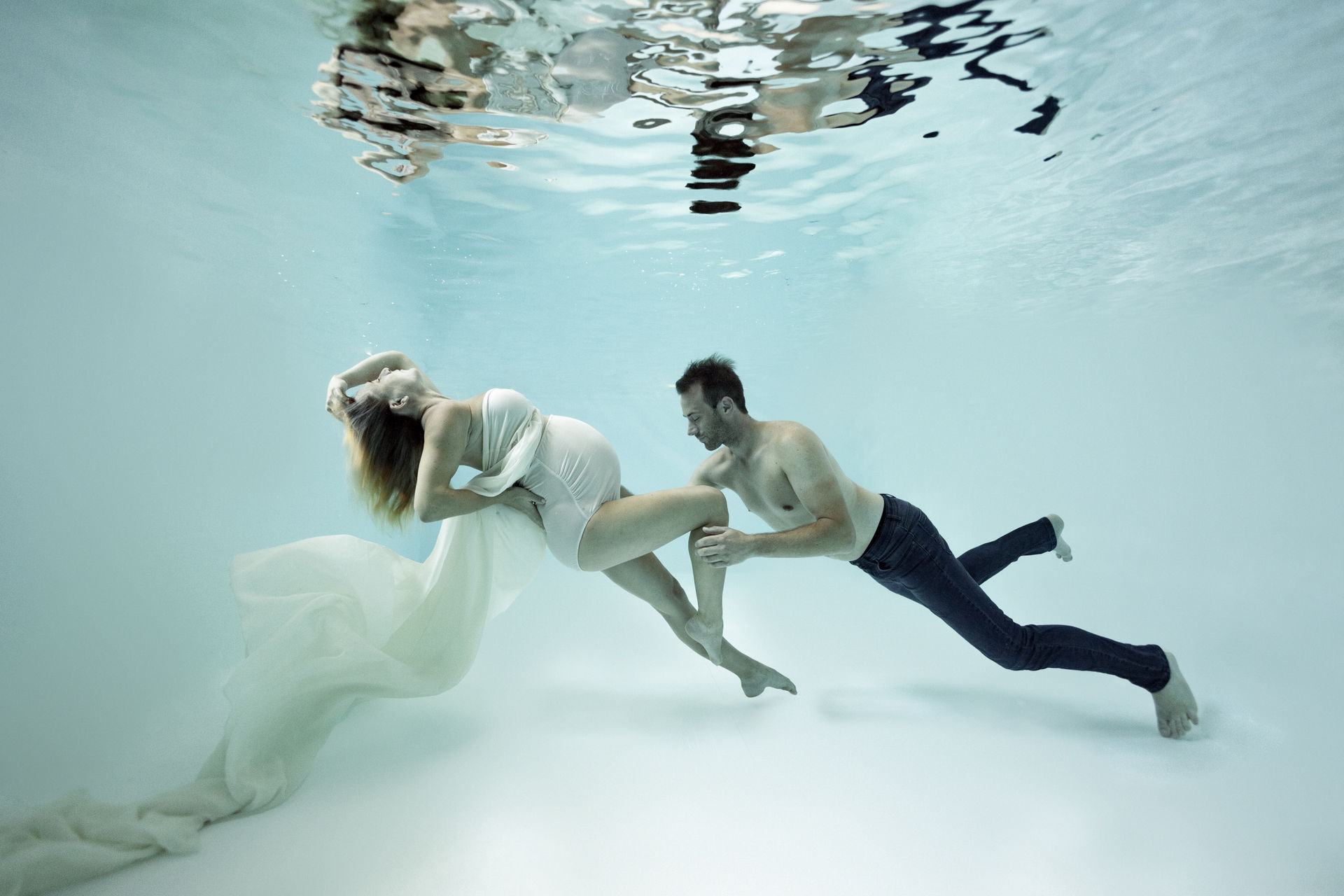 Paar in weißer Kleidung schwebt unter Wasser