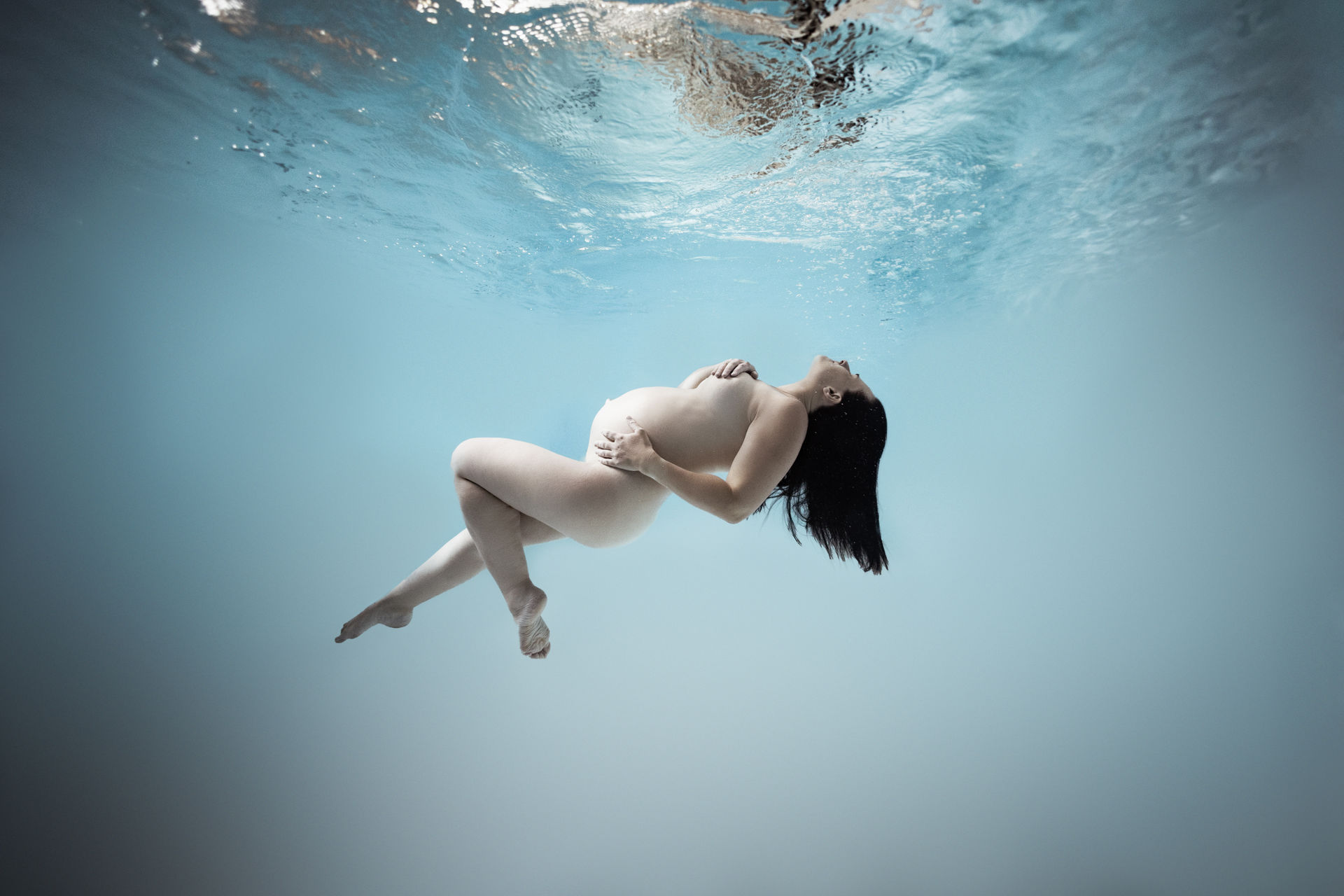 Schwangerschaftsportrait in blauem Unterwasserlicht