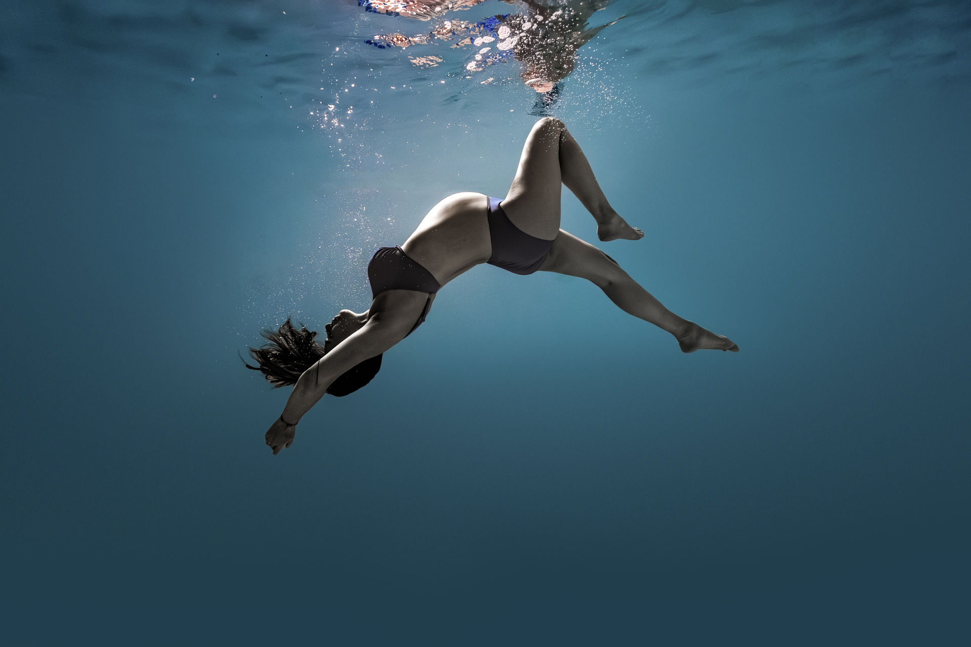 Dynamische Unterwasserpose in dunklem Outfit