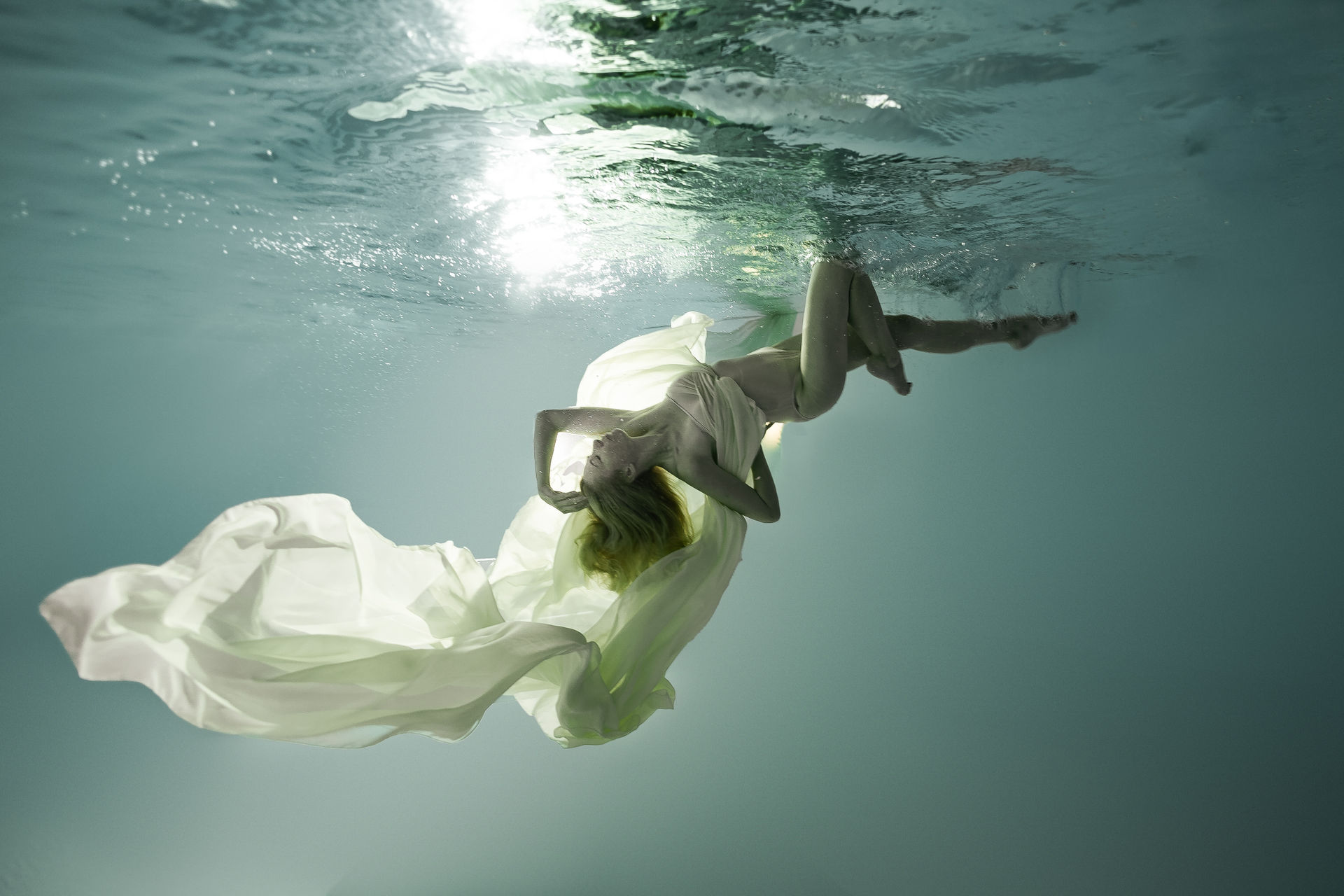 Schwebende Frau mit grünem Kleid unter Wasser